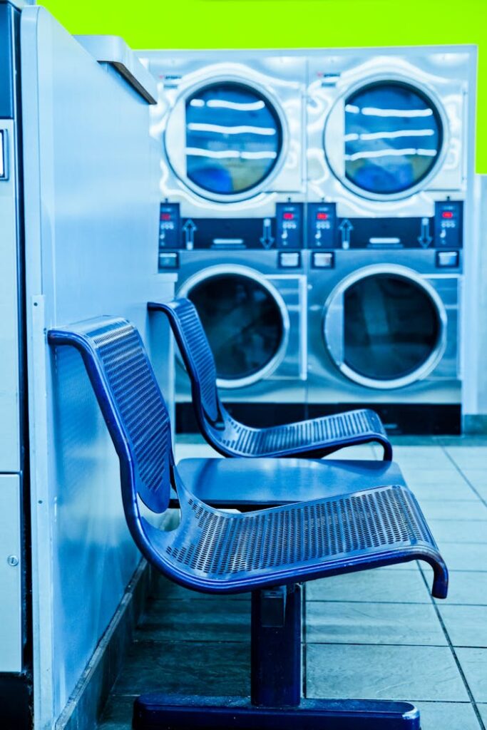 Bright laundromat interior featuring blue chairs and industrial washing machines.